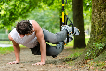 man in city park doing suspension trainer sport