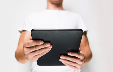 Man in white t-shirt using tablet pc, white wall on background