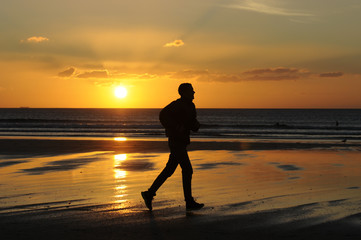 man running on the beach at sunset