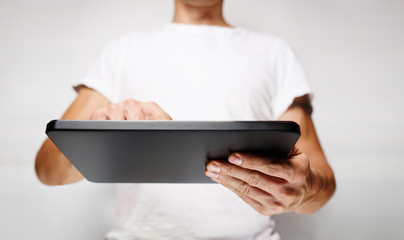 Man in white t-shirt using tablet pc, white wall on background