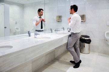 Man getting dressed in a public restroom with mirror