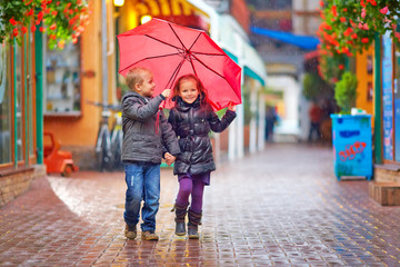 happy kids walking under the rain on colorful street