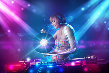 Energetic Dj girl mixing music with powerful light effects