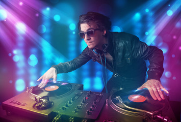 Obraz na płótnie Canvas Dj mixing music in a club with blue and purple lights