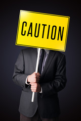 Businessman holding a caution sign
