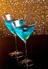 two glasses of fresh blue cocktail with ice on wood table