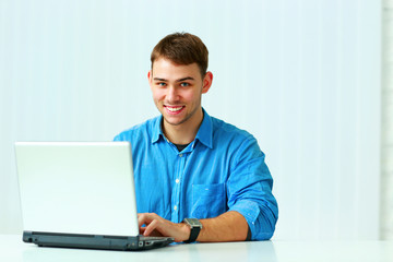 Young smiling businessman typing on the laptop 