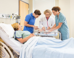 Doctor Examining Babygirl While Parents And Nurse Looking At Her