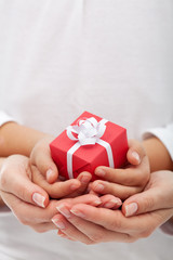 The joy of giving - small gift box in woman and child hands