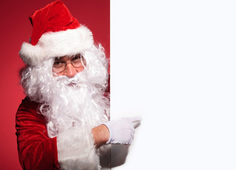 santa claus is presenting a blank board by pointing