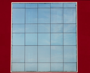 Glass facade with sky reflected on red wall