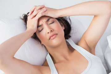 Fototapeta premium Sleepy woman suffering from headache in bed