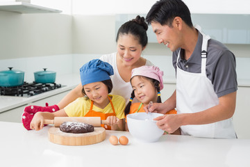 Happy family of four preparing cookies in kitchen