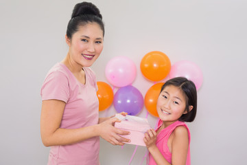 Woman giving gift box to a little girl at a birthday party