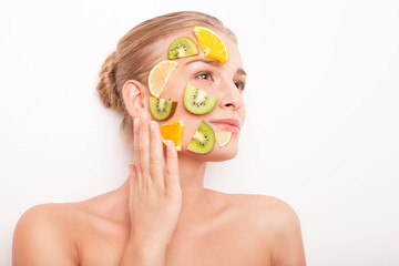 Smiling woman with fruit mask on her face isolated