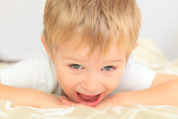 portrait of happy little boy lying in bed