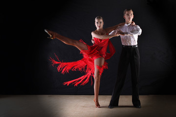 Latino dancers in ballroom against on black