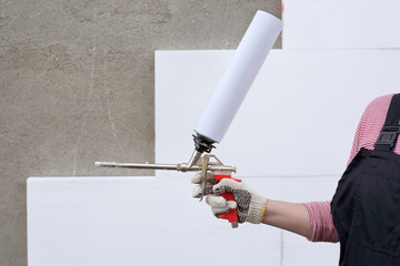 Worker hold polyurethane expanding foam glue gun applicator - obrazy, fototapety, plakaty