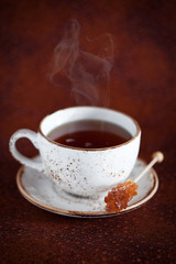 Cup of hot tea and rock candy sugar stick, selective focus