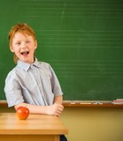 Little funny redhead schoolboy near blackboard 
