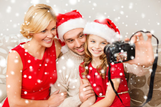 smiling family in santa helper hats taking picture