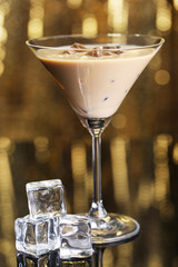 Baileys liqueur in glass on golden background