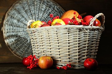 Juicy apples and pumpkin in wooden basket on table close-up