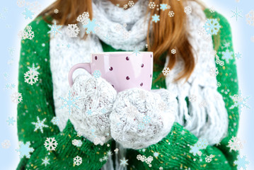 Women hands in mittens with cup on blue background