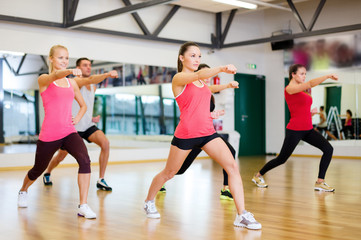 group of smiling people exercising in the gym