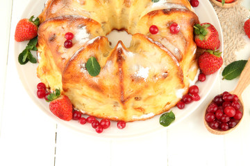 Tasty homemade cake with berries, on white wooden table
