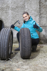 Fototapeta na wymiar Young smiling woman driver replacing tires, showing OK sign