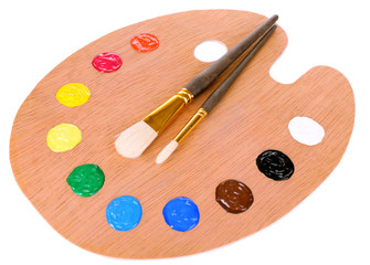 Wooden art palette with paint and brushes isolated on white