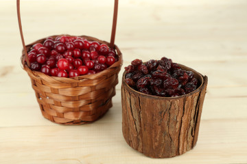 Fresh and dry cranberry in baskets on wooden table
