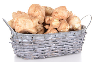 Topinambur roots in wicker basket isolated on white