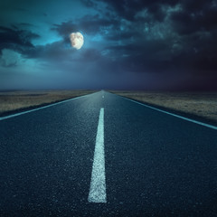 Driving on asphalt road at night towards the moon