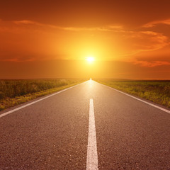 Driving on asphalt road at sunset towards the sun III