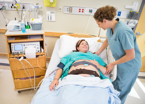 Nurse Communicating With Pregnant Patient Lying In Hospital Bed
