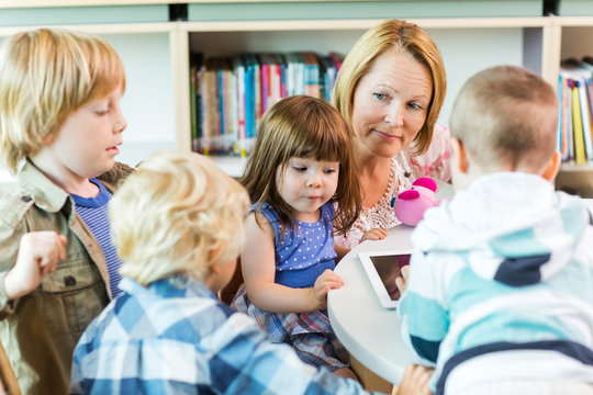 Teacher With Students Using Digital Tablet In Library