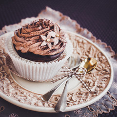 Beautiful chocolate cupcake on vintage plate. 