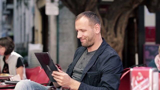 Young man with tablet computer drinking coffee in cafe