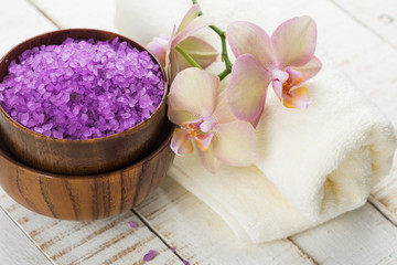 Spa concept. Sea salt in bowl with flowers and towel on white wo