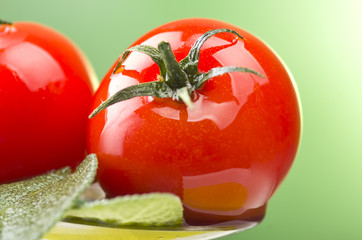  Spoon with little tomatoes and oil on a green background