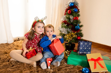 Obraz na płótnie Canvas little kids on rug opening Christmas Presents
