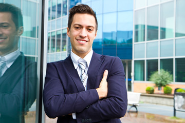Fototapeta premium Smiling young businessman standing outside a building