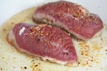 Duck breast being fried in pan