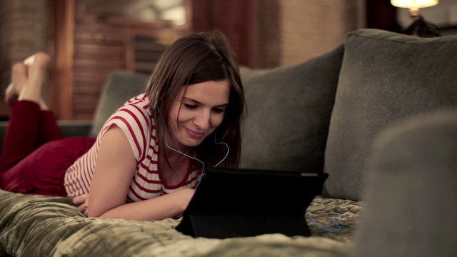 Young woman watching movie on tablet computer on sofa
