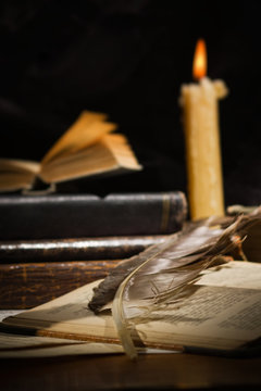 Old books and candles on wooden table