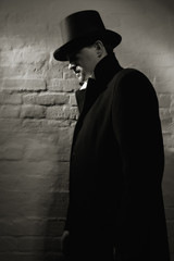 Fototapeta na wymiar Man in the black coat, top hat and in a red tie
