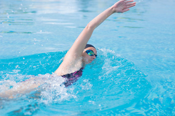 Woman in goggles swimming front crawl style