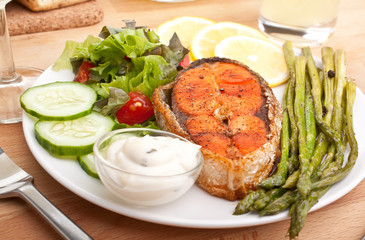 salmon served with vegetable salad, asparagus, lemon and sauce